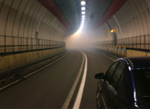 Car driving through tunnel towards light and smoke